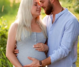 Expecting couple standing together outdoors holding belly Expecting couple standing together outdoors holding belly