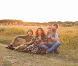 Family sitting together in open field smiling Family sitting together in open field smiling