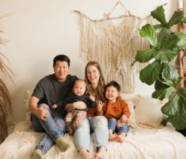 Family sitting together indoors with neutral backdrop Family sitting together indoors with neutral backdrop