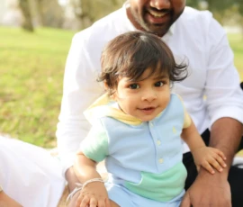 Father sitting with toddler outdoors during family session Father sitting with toddler outdoors during family session