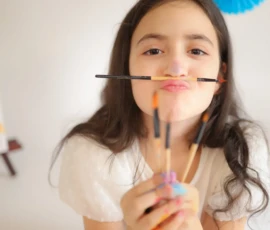 Girl holding brushes and smiling during celebration portrait