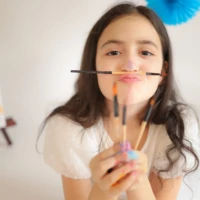 Girl holding brushes and smiling during celebration portrait Girl holding brushes and smiling during celebration portrait