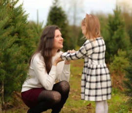 Mother and daughter smiling in Christmas tree field scaled 1 Mother and daughter smiling in Christmas tree field scaled 1