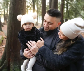 Parents cuddling baby in forest during family session Parents cuddling baby in forest during family session