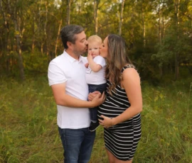 Parents holding baby close during outdoor family portrait Parents holding baby close during outdoor family portrait