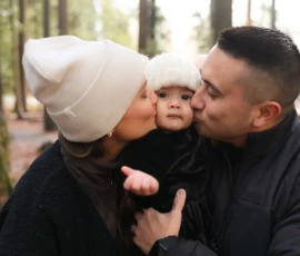 Parents kissing baby during cozy family moment Parents kissing baby during cozy family moment