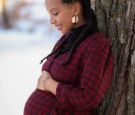 Pregnant woman leaning against tree during maternity session Pregnant woman leaning against tree during maternity session