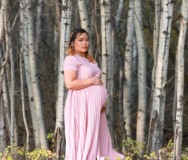 Pregnant woman standing among trees wearing pink dress Pregnant woman standing among trees wearing pink dress
