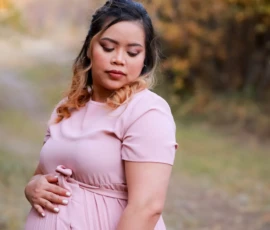 Pregnant woman standing outdoors holding belly Pregnant woman standing outdoors holding belly