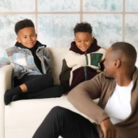 Siblings adn father Sitting Together in Christmas Pajamas Siblings adn father Sitting Together in Christmas Pajamas