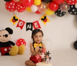 Toddler sitting with birthday cake in themed cake smash setup