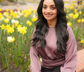 Woman sitting among flowers smiling at camera