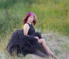 Woman sitting in dark tulle dress outdoors during portrait
