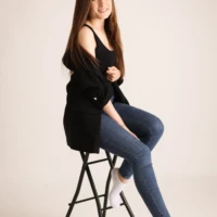 Woman sitting sideways on stool during studio photo session Woman sitting sideways on stool during studio photo session