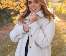 Woman standing outdoors wearing coat during fall portrait